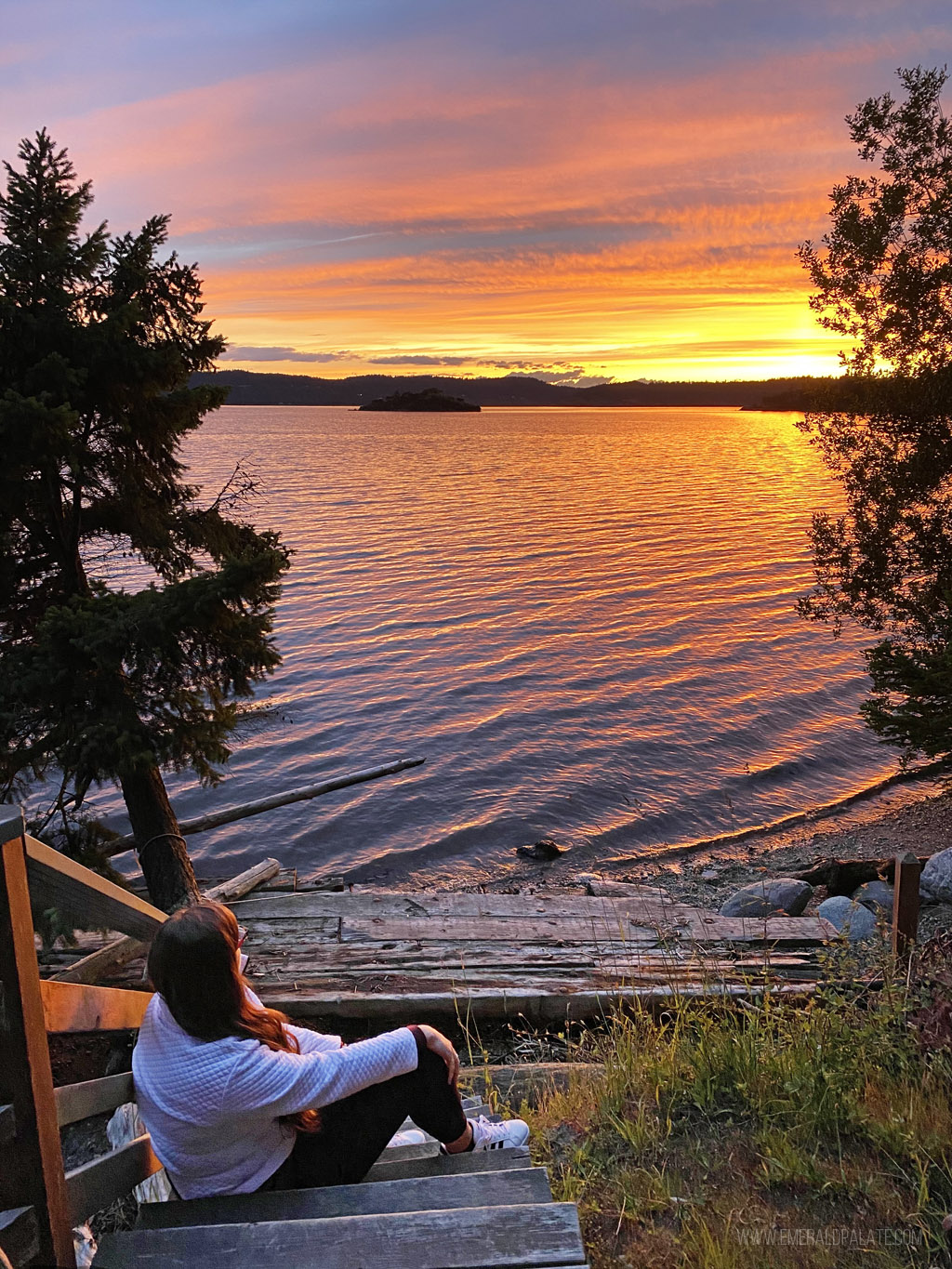 woman sitting on dock overlooking water at sunset in Skagit County