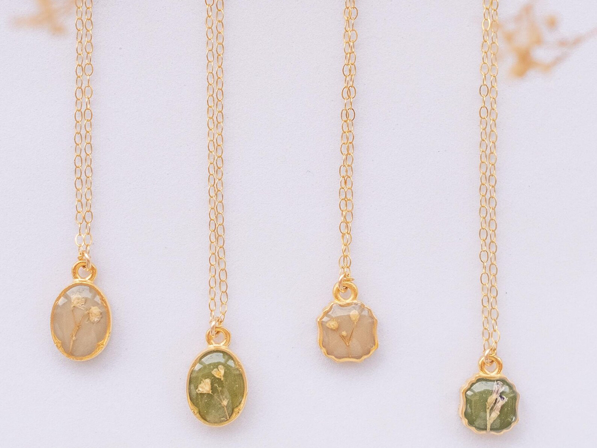 four romantic, vintage-looking delicate necklaces with pressed flower charms on dainty gold chains from one of the best Seattle jewelry makers