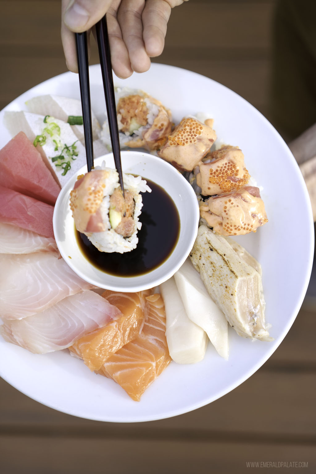 person dipping sushi into sou sauce