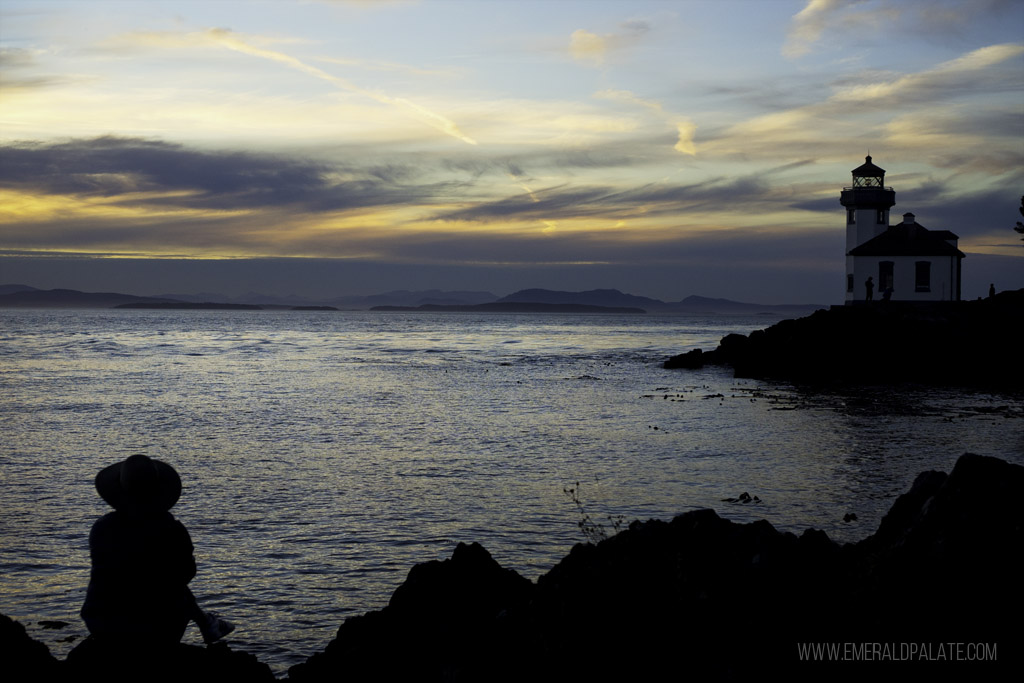 view of a woman watching Lime Kiln Park lighthouse at sunset in San Juan Island on a day trip