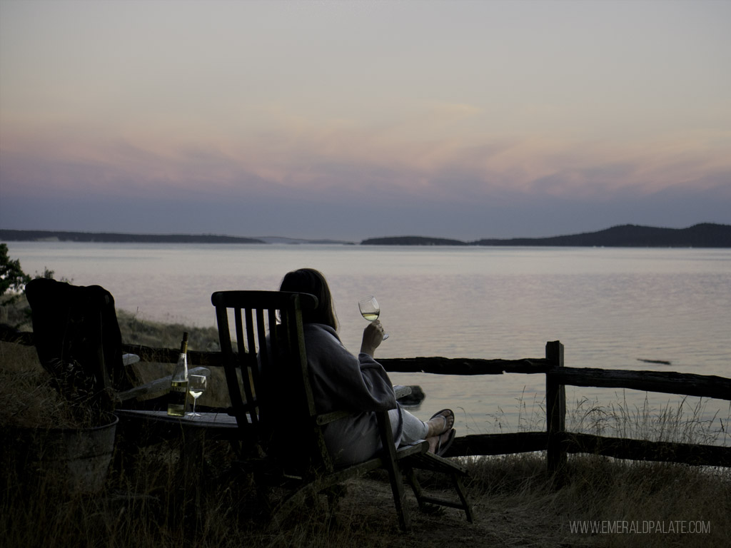 woman drinking wine looking at waterfront at sunset on one of the San Juan Islands