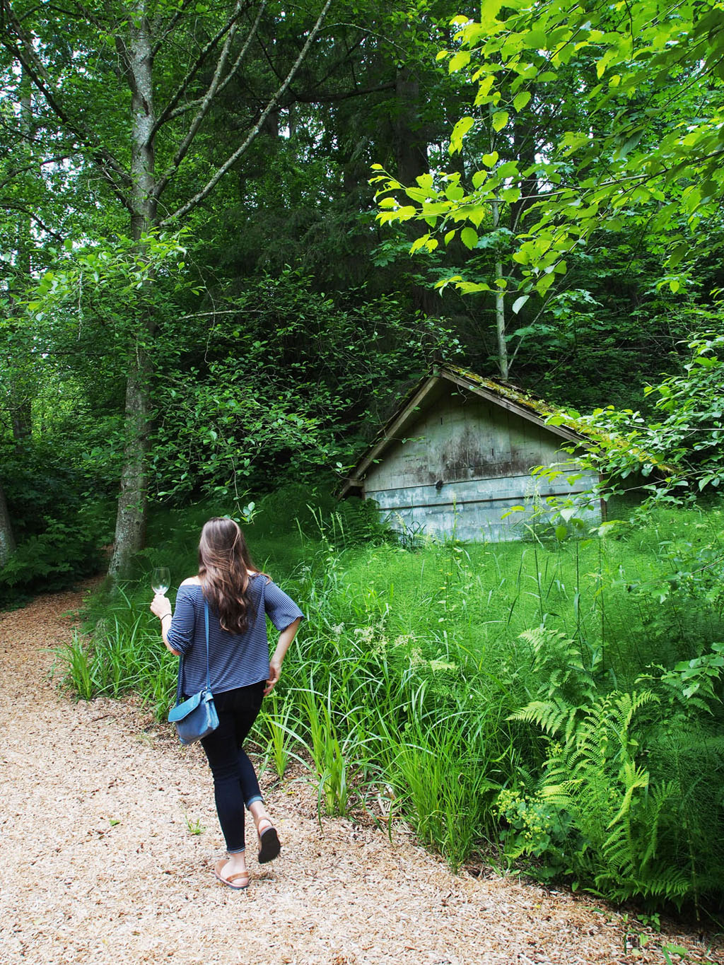 woman walking in a lush winery forest with wine, a scenic day trip from Seattle