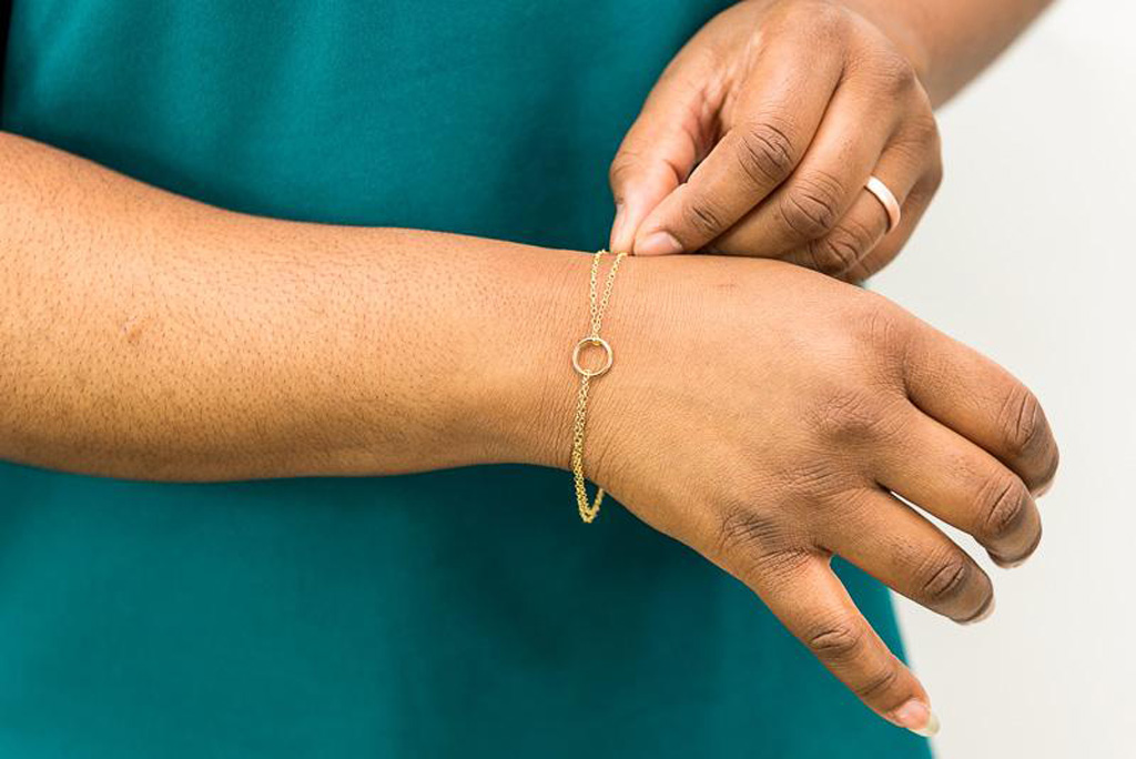 woman adjusting a minimal gold bracelet from a Seattle jewelry maker