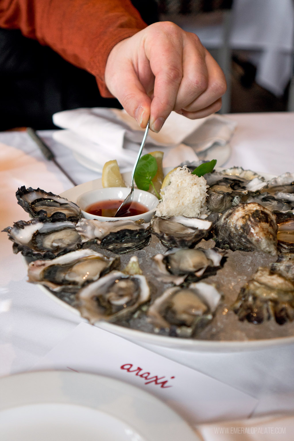 person dipping spoon in mignonette on an oyster platter in Whistler Village
