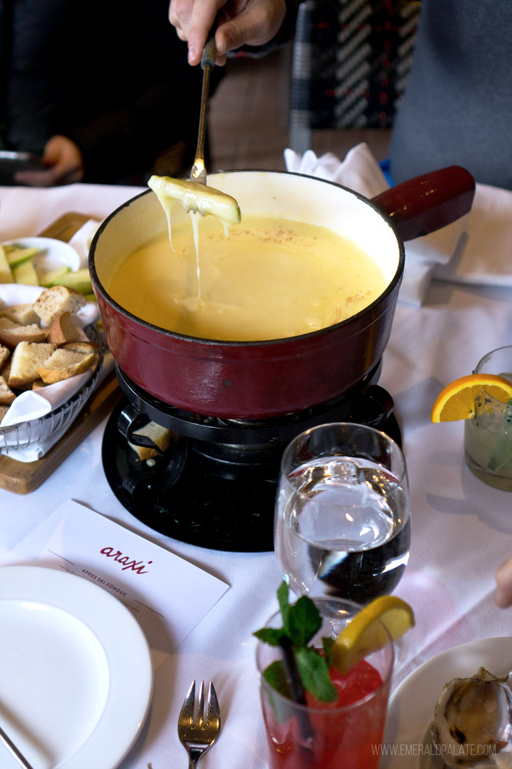 person dipping fondue fork with a pickle on it into fondue