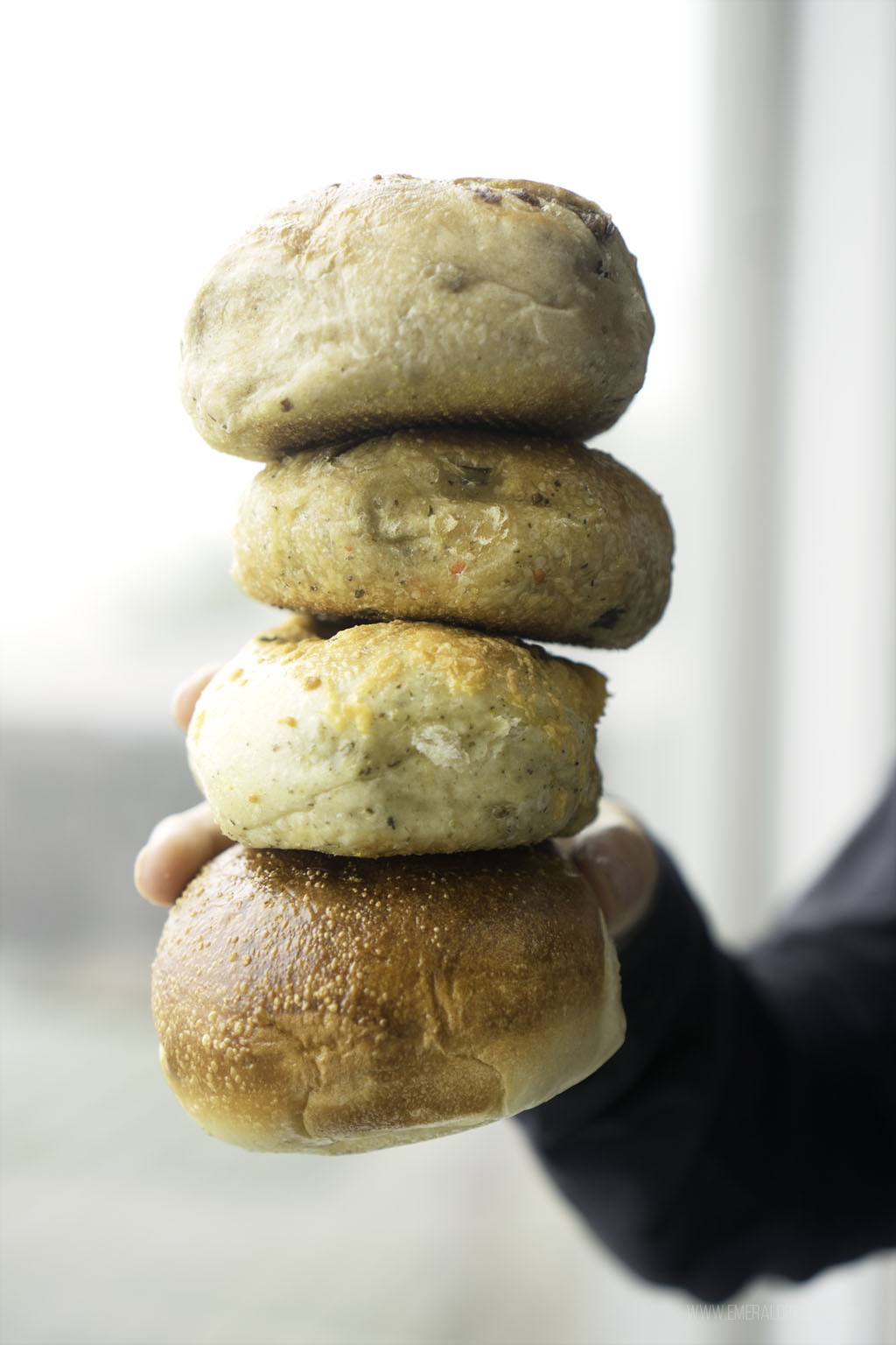 person holding stack of 4 bagels