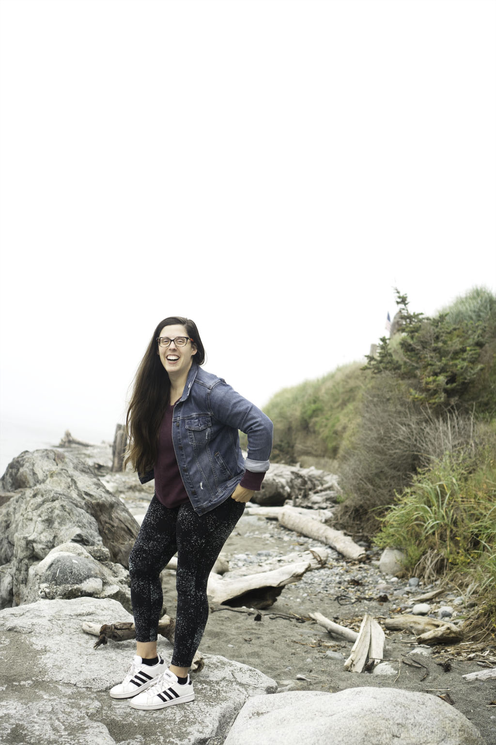 woman laughing on driftwood at Hastie Beach