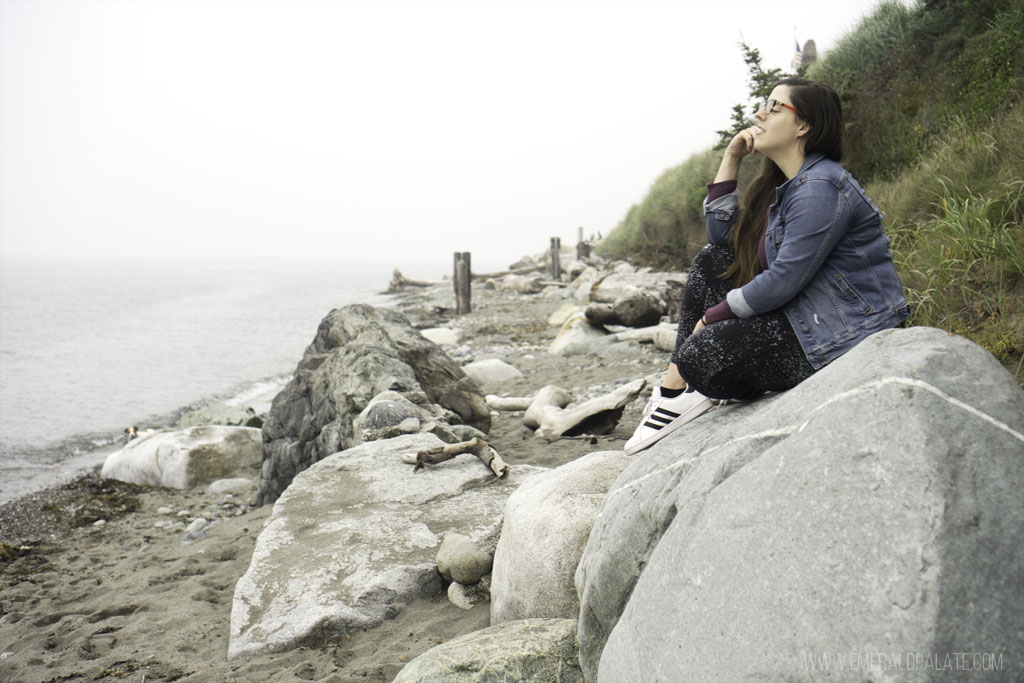 woman sitting on rock overlooking ocean on a beach on an island close to Seattle