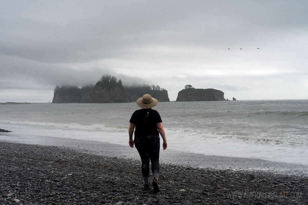 Rialto Beach Washington woman walking on beach toward sea stacks in distance on Rialto Beach, one of the best Washington coast attractions