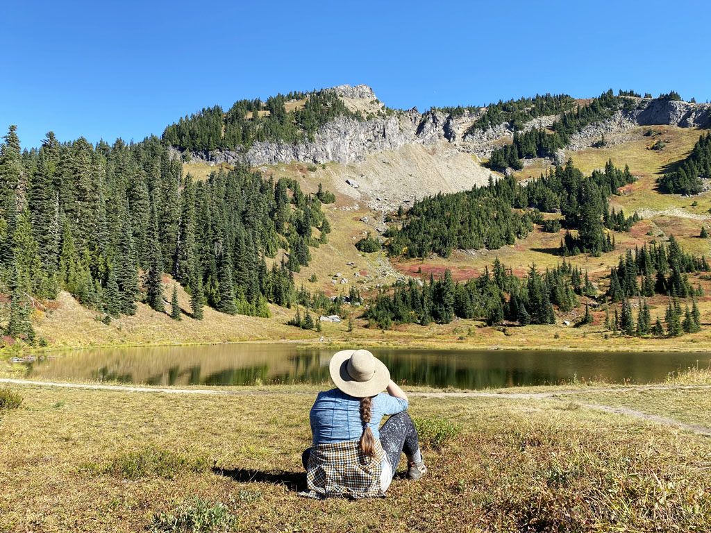 woman sitting looking out at Naches Peak during a hike on a Mt Rainier day trip