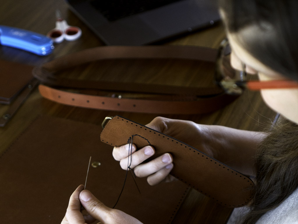 woman stitching a leather purse, a unique Seattle experience gift idea