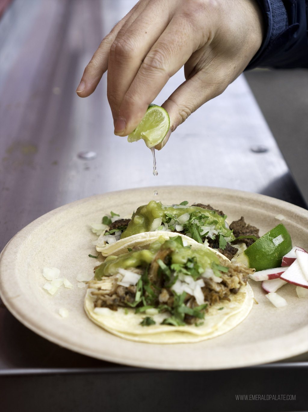 person squeezing lime juice on tacos