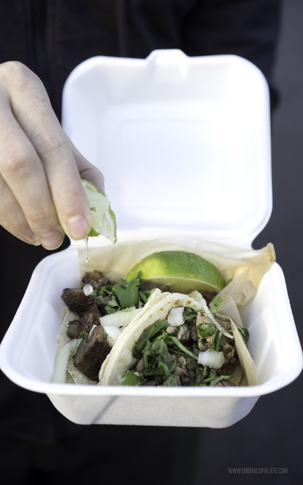 person squeezing lime over carne asada tacos in Seattle