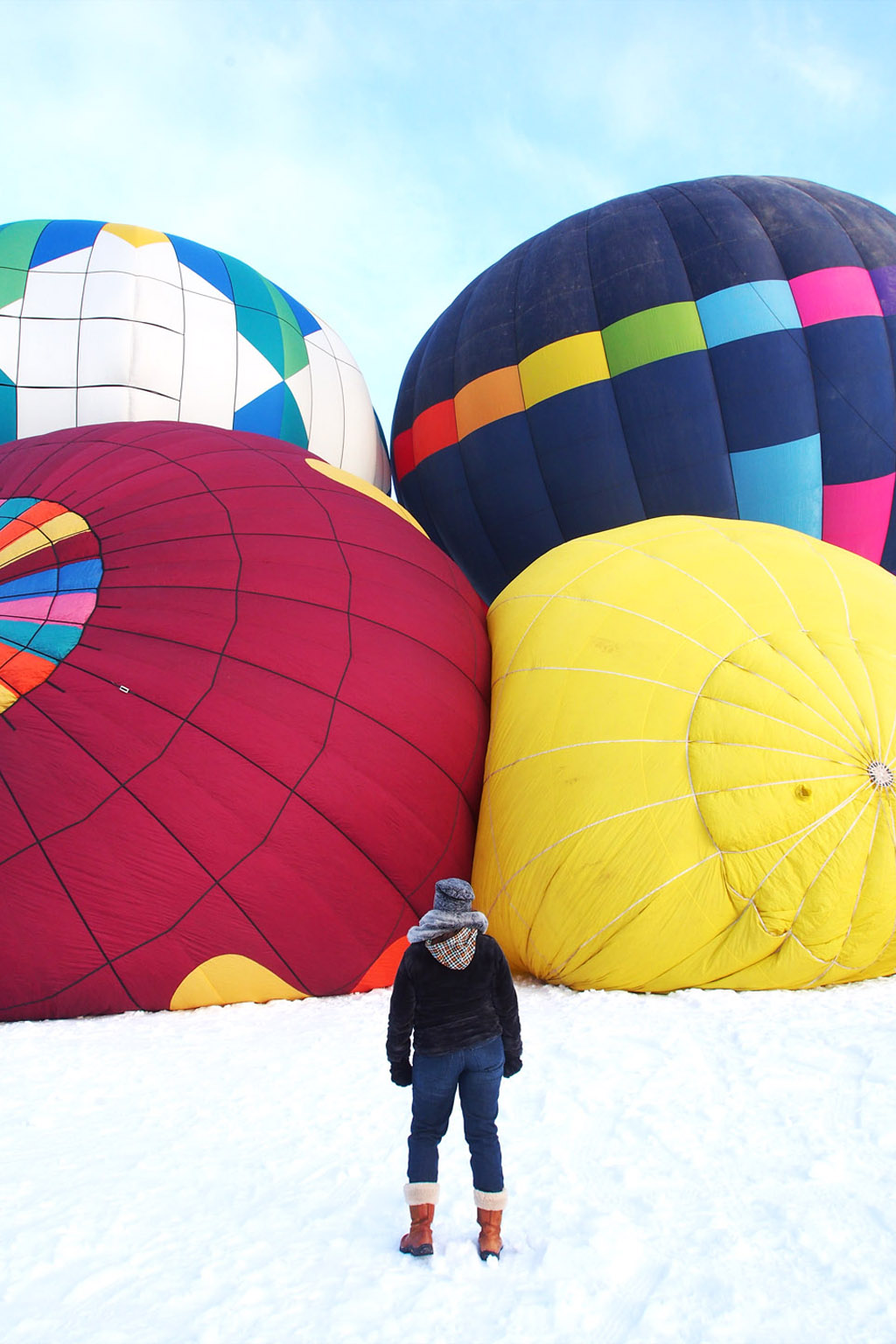 woman standing in front of 4 hot air balloons being blown up