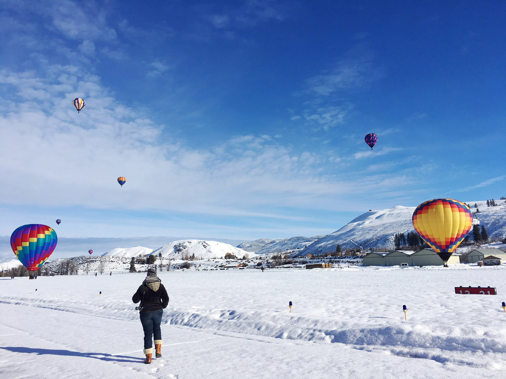 woman walking in a field of hot air balloons in winter