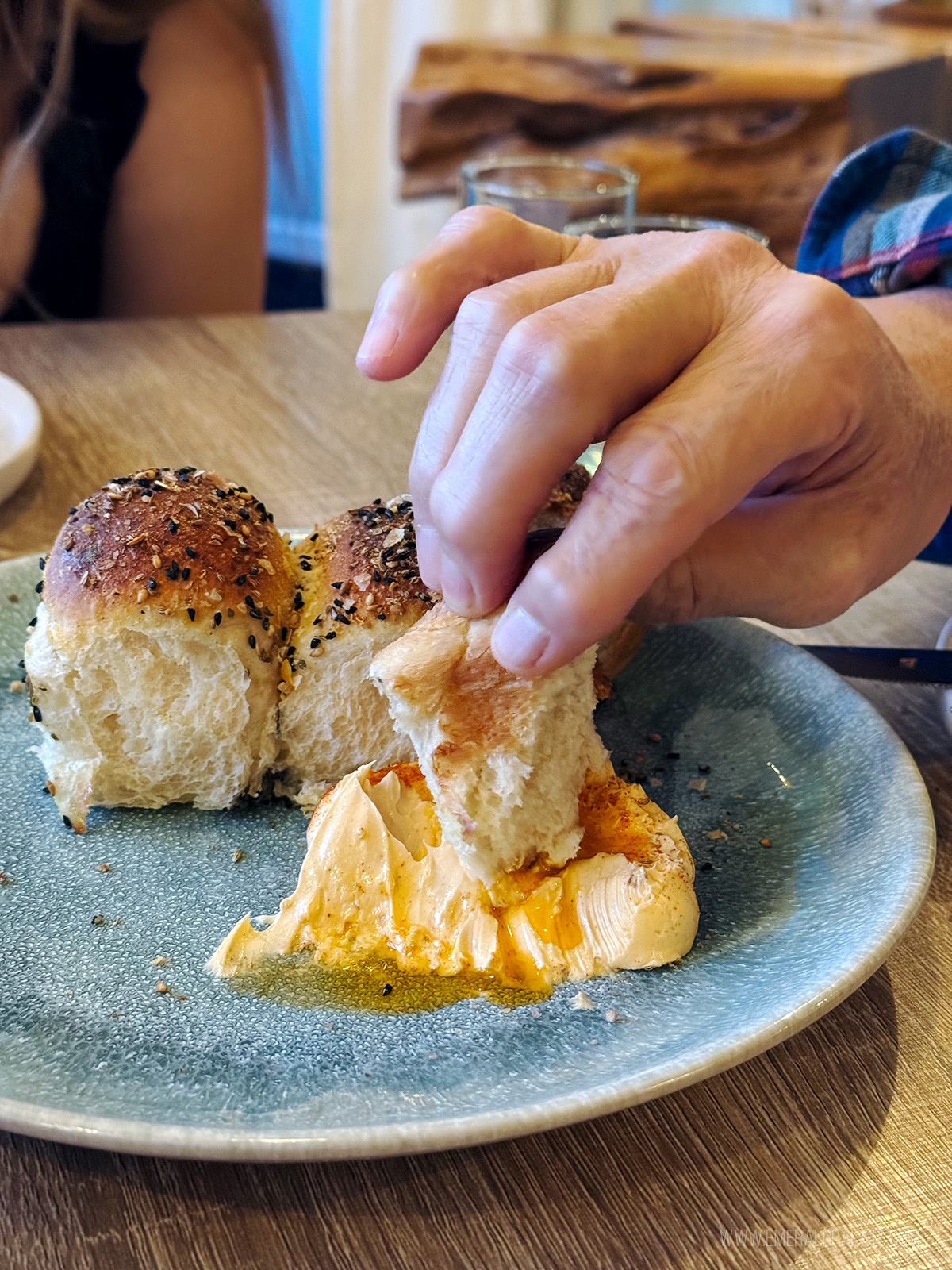 person dunking a roll into whipped butter