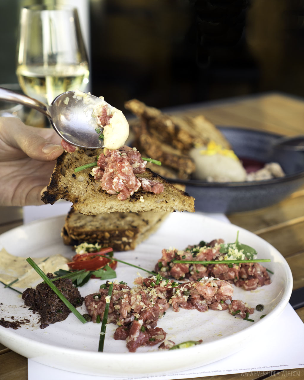 person spooning steak tartare on toast from one of the best fine dining spots in Seattle