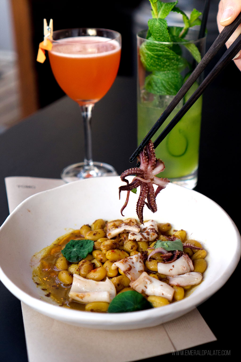 person picking up a baby octopus with chopsticks at one of the best fine dining restaurants in Seattle