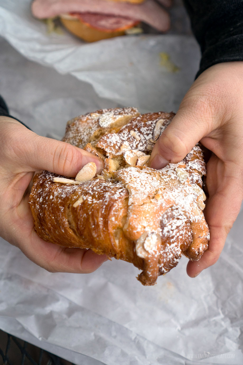 person breaking a croissant 