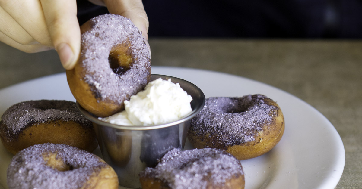 person dunking mini doughnut into cream at a festival on a Seattle events calendar