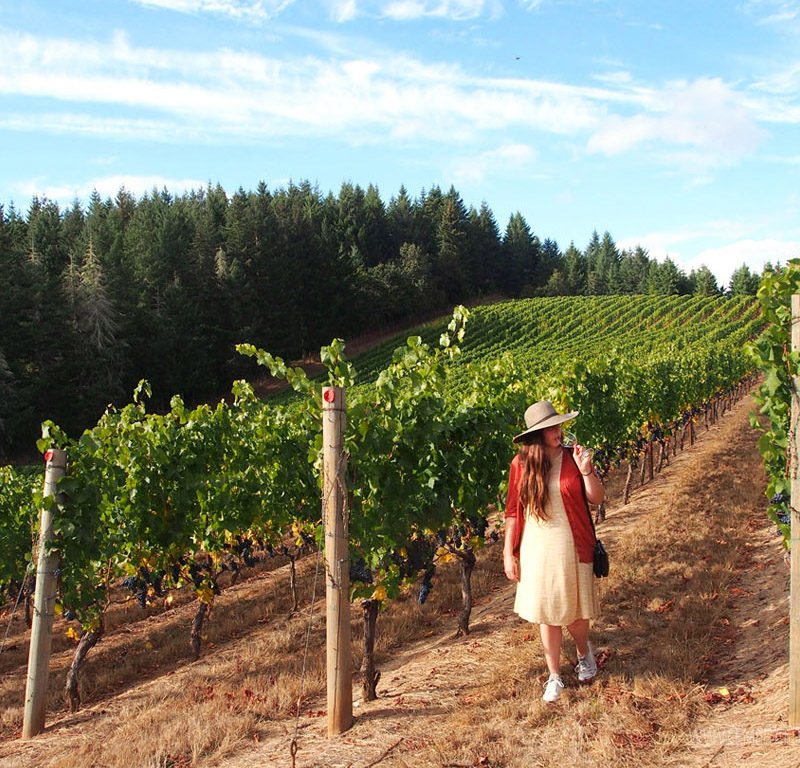 woman walking through vineyards at one of the best wineries in Willamette Valley