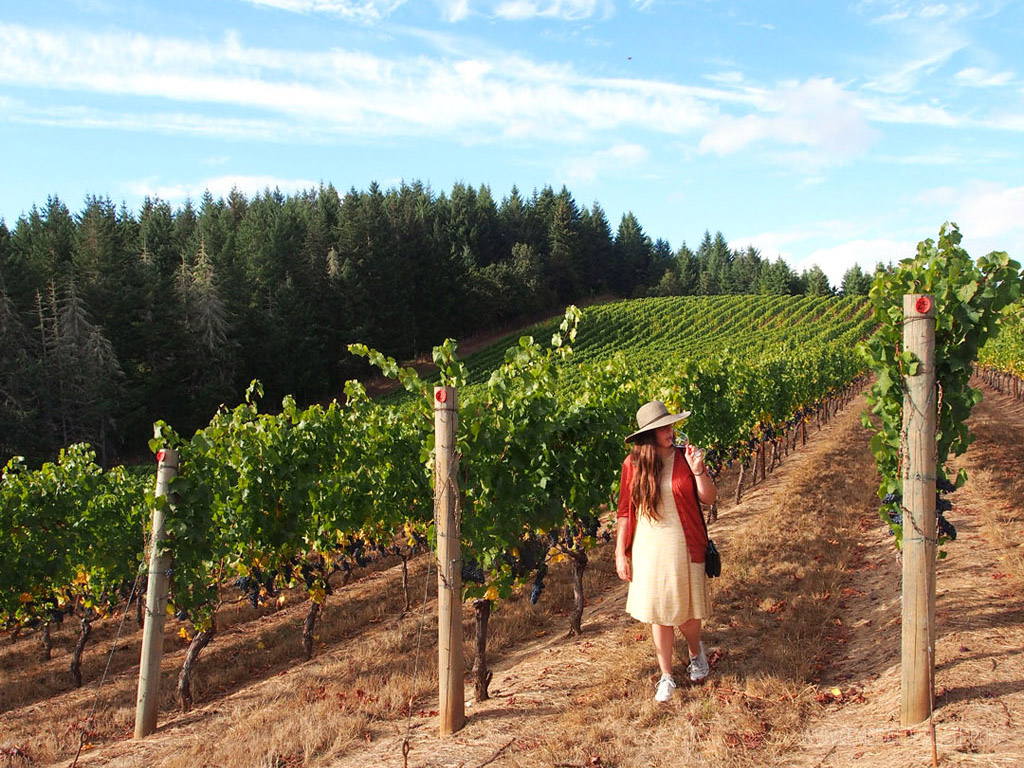 woman walking through vineyards at one of the best wineries in Willamette Valley