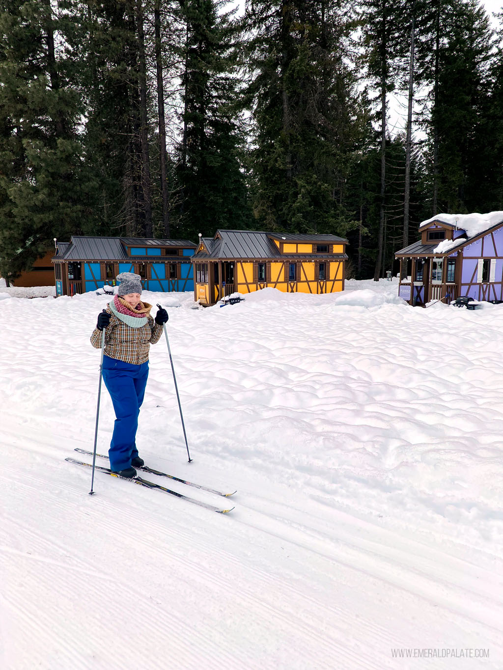 woman cross country skiing in front of Leavenworth tiny homes