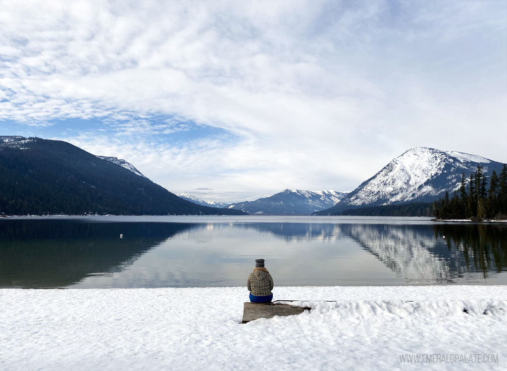 woman sitting in front of lake to take a break from cross country skiing in Washington