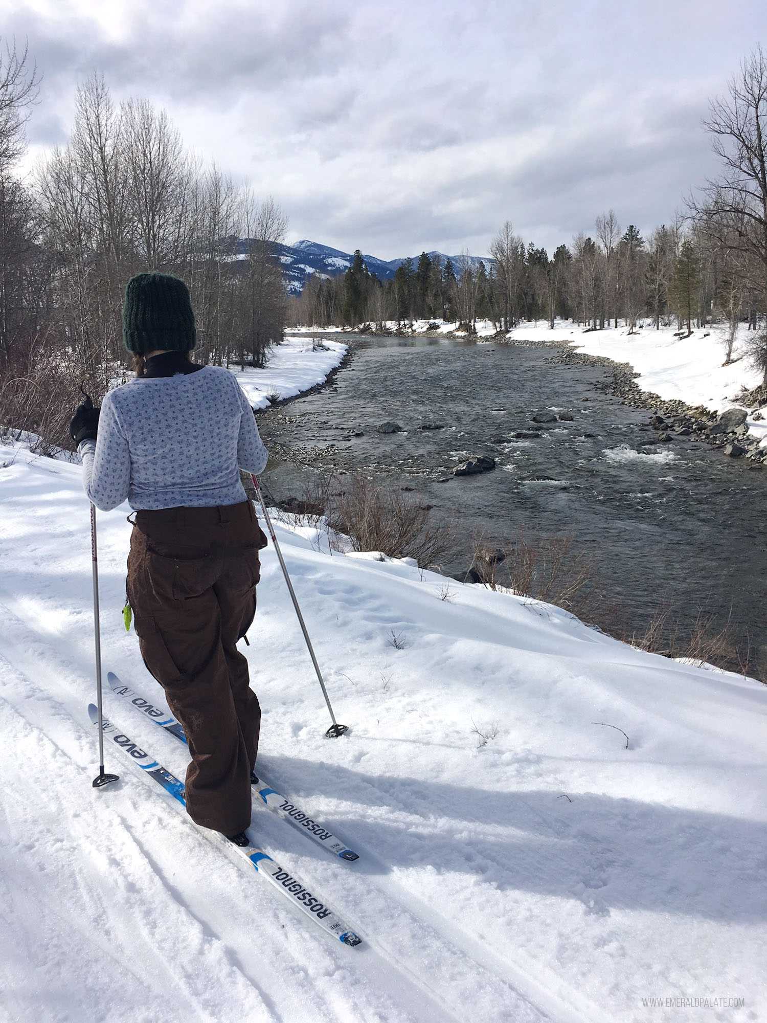 woman cross country skiing on a trail along a river in Winthrop, Washington
