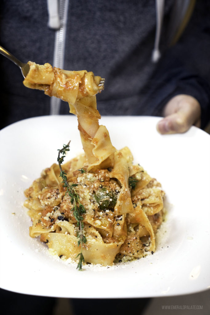 person pulling forkful of pasta on a food tour of Pike Place Market