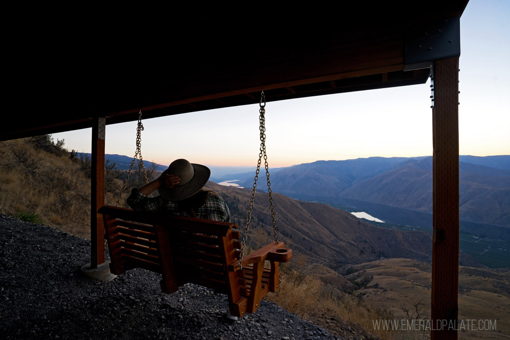 woman enjoying sunset views of the valley from a porch swing at one of the most romantic Airbnbs in Washington state