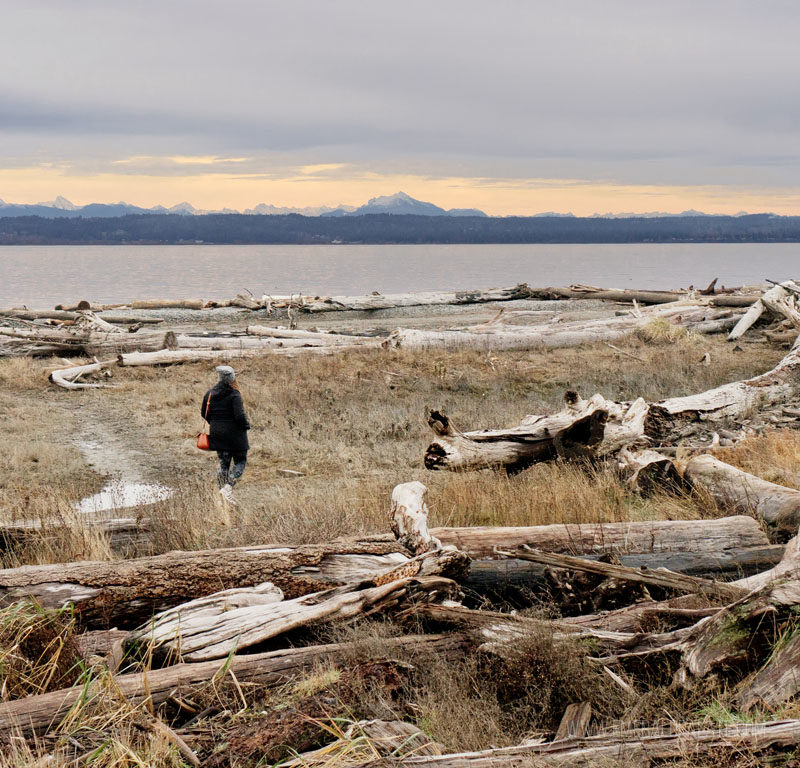 woman walking along the beach at sunset on Camano Island, and island off Seattle