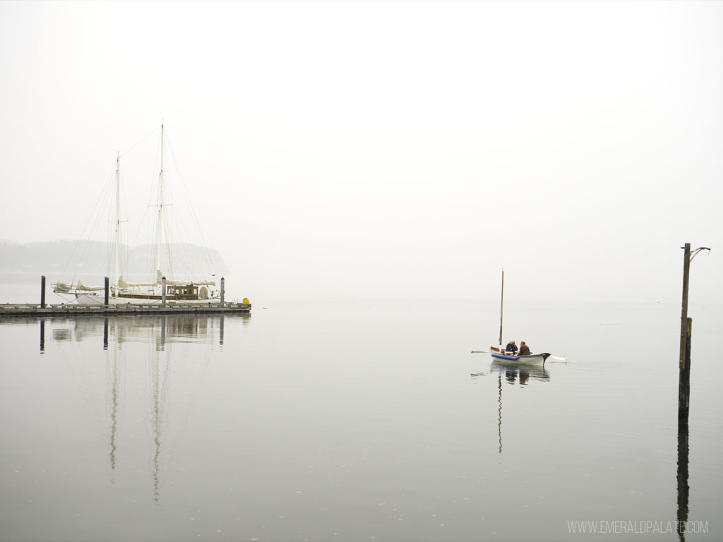 older men canoeing on the water near a dock in the mist on Whidbey | Best Road Trips from Seattle