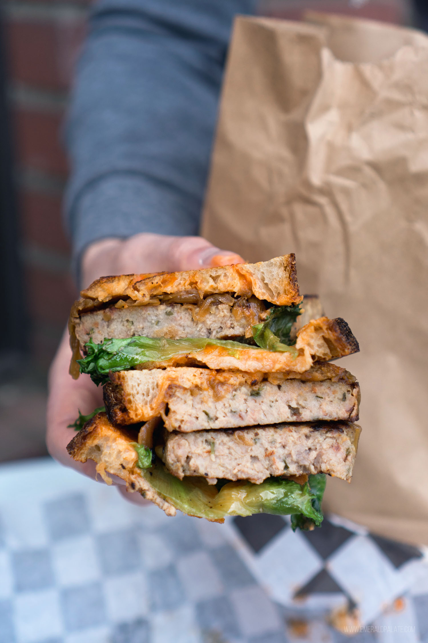 person holding meatloaf sandwich halves stacked on top of each other