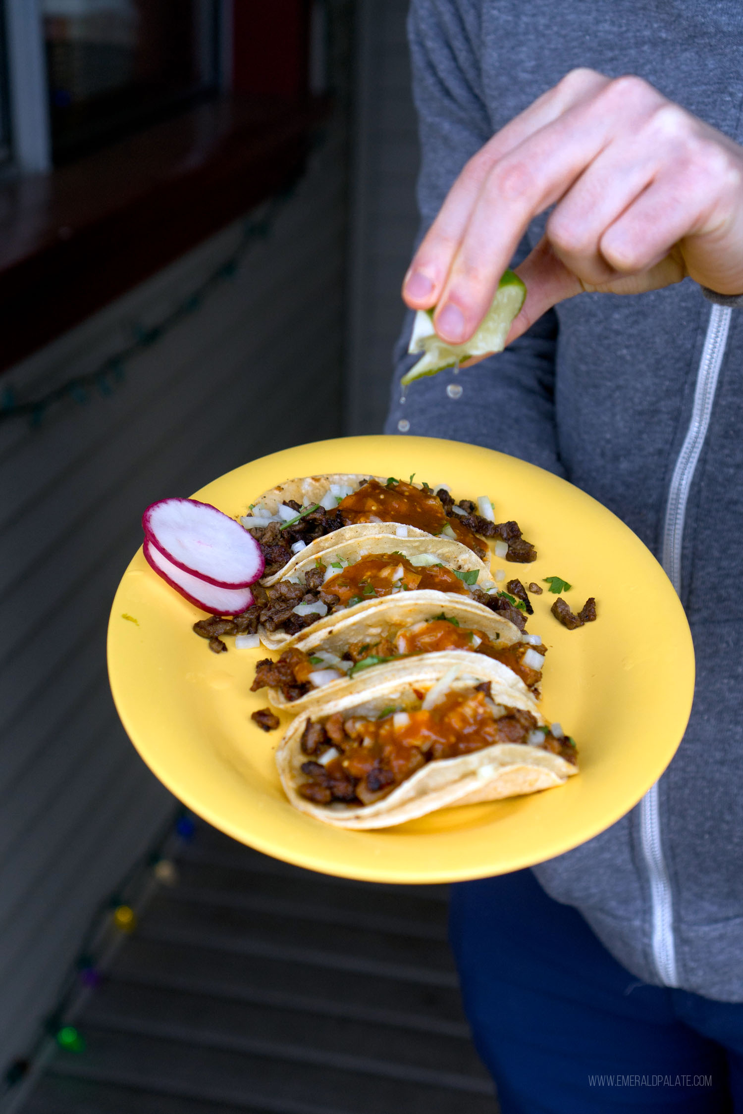 person squeezing lime over a plate of tacos from a place to eat on Vashon Island