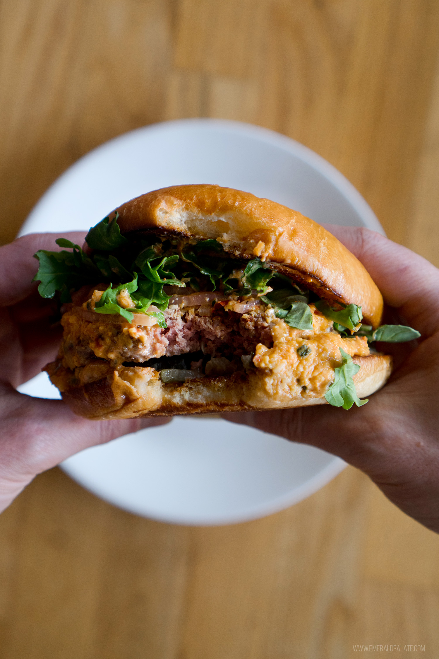 person holding a gourmet burger with a bite taken out of it