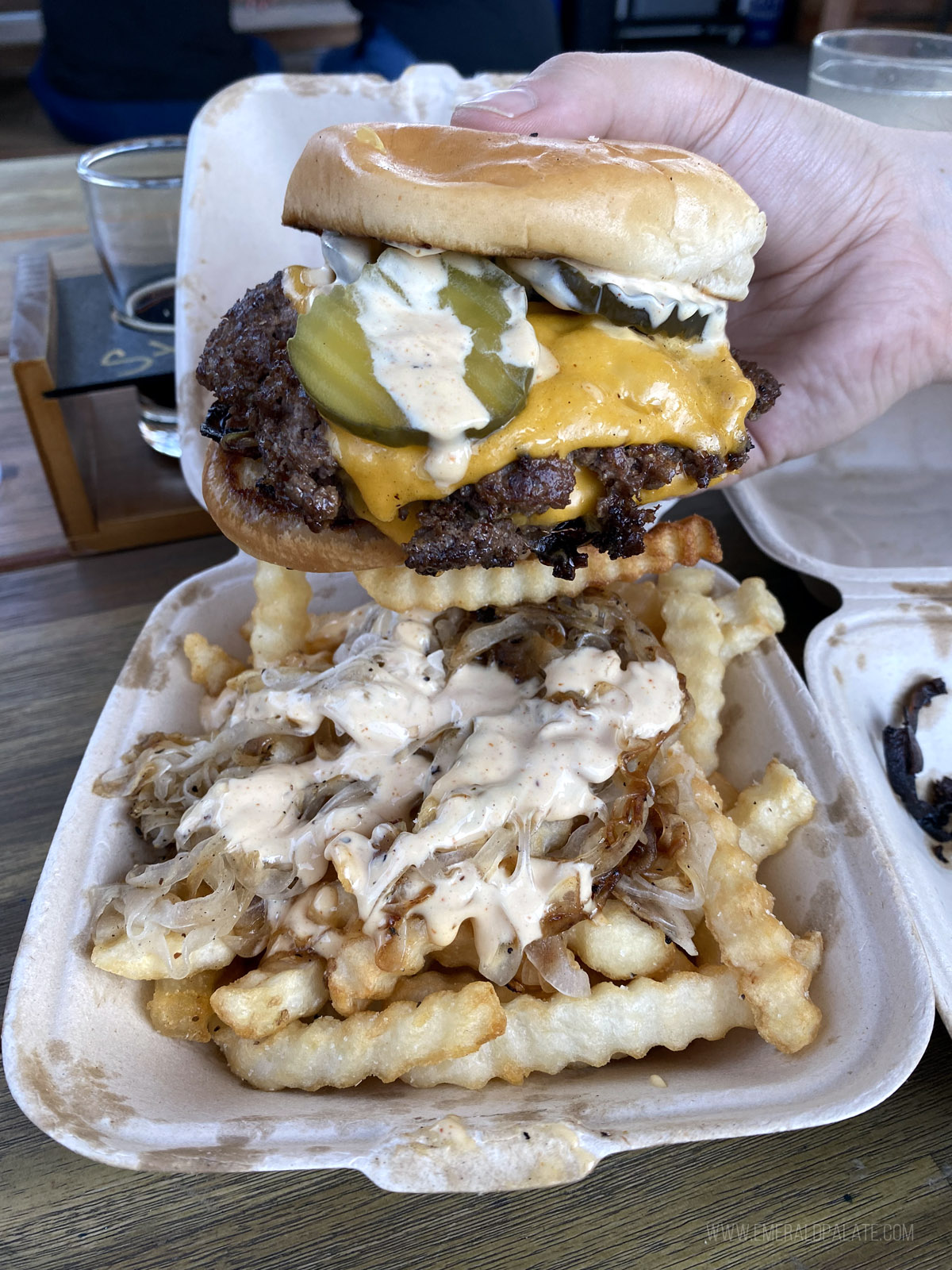 person holding a smash burger, one of the best burgers in Seattle