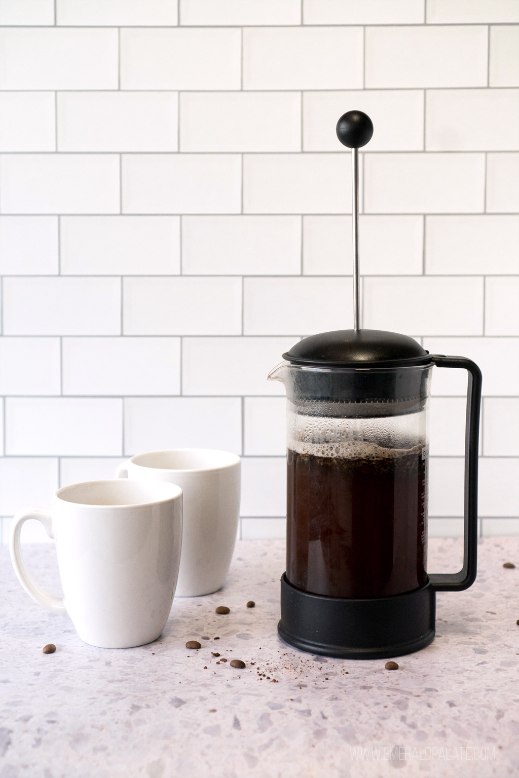 coffee steeping in a French press next to two mugs