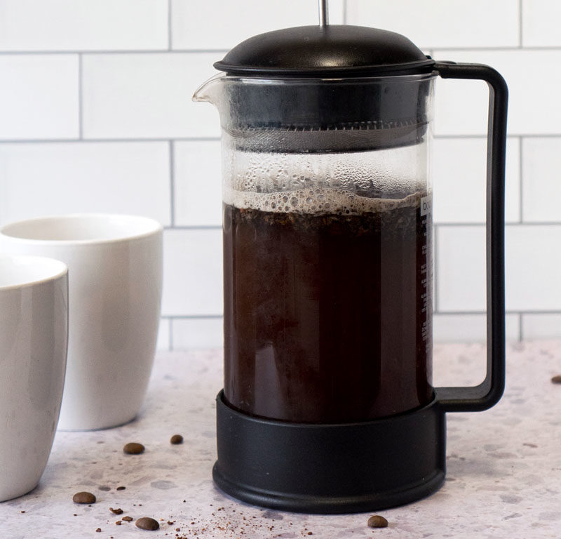 best coffee for a French press steeping next to two mugs