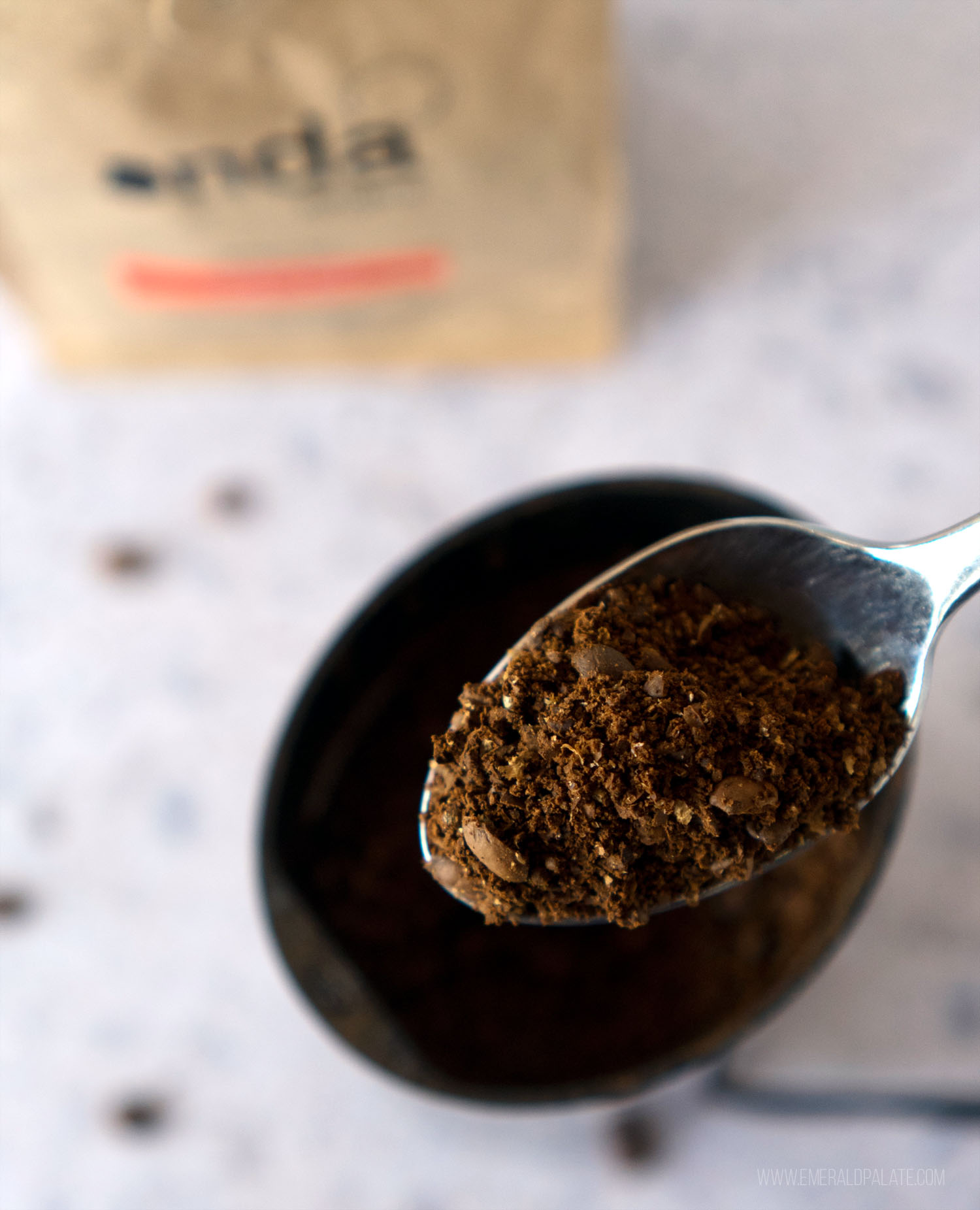 person spooning some ground coffee for French press