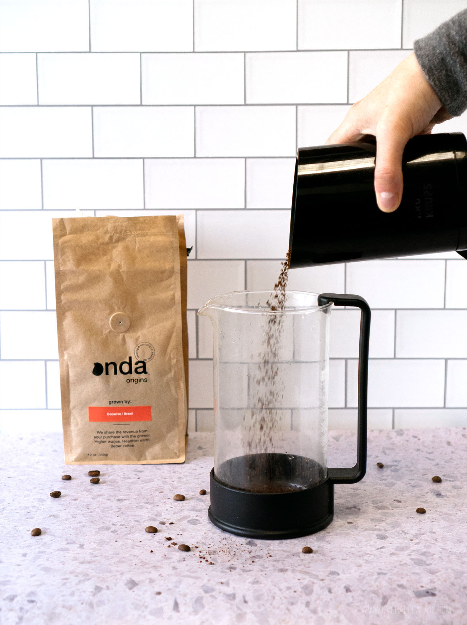 coffee grounds being poured from a grinder into a French press