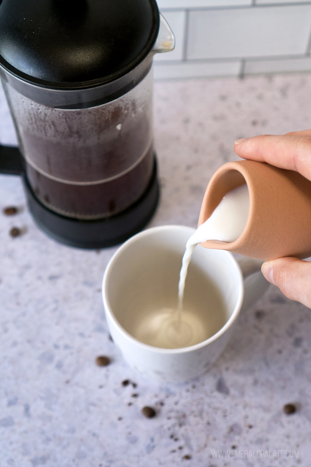 person pouring milk into a coffee mug