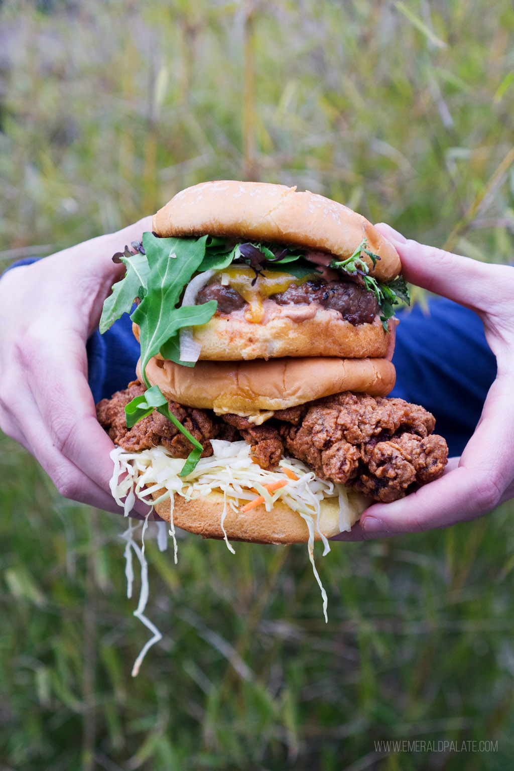 person holding a stack of burger and fried chicken sandwiches from Ursa Minor on Lopez Island