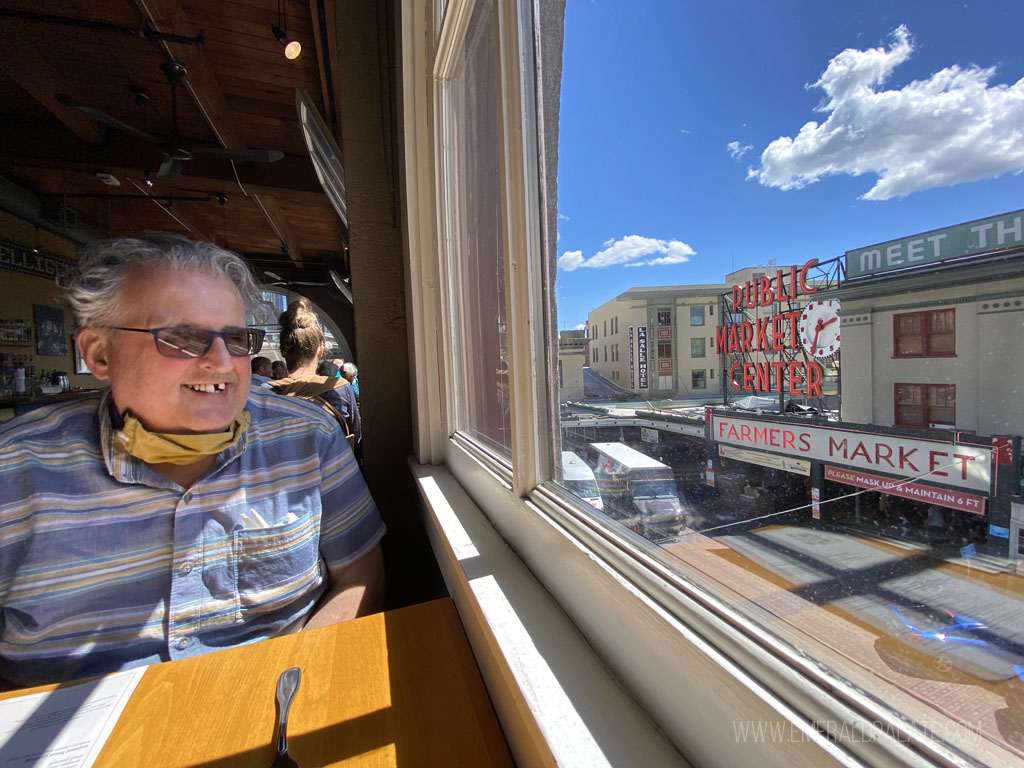 man eating at a restaurant in Seattle with great views of the Pike Place Market sign