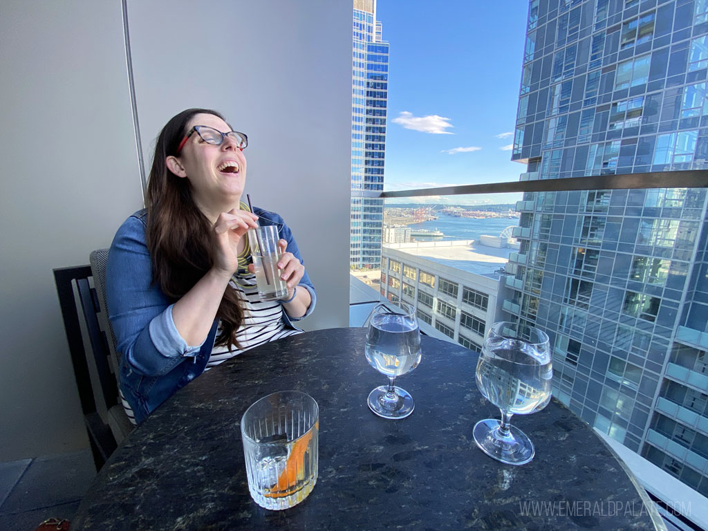 woman laughing while drinking a cocktail at one of the best rooftop bars in Seattle with a view