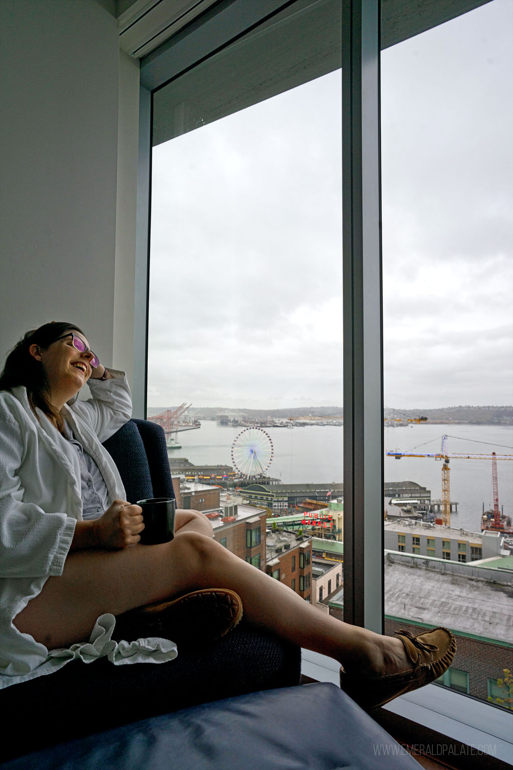 woman laughing while enjoying coffee from a hotel room with a view of downtown Seattle