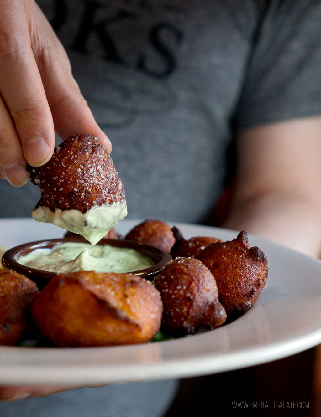 person dipping beignet into sauce at 5th Street Public Market restaurant