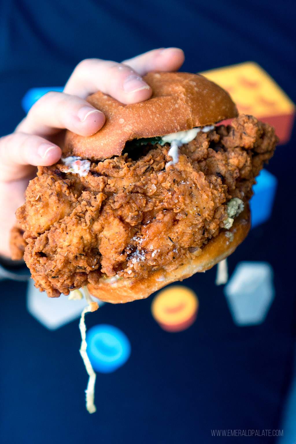 person holding a fried chicken sandwich from Seattle