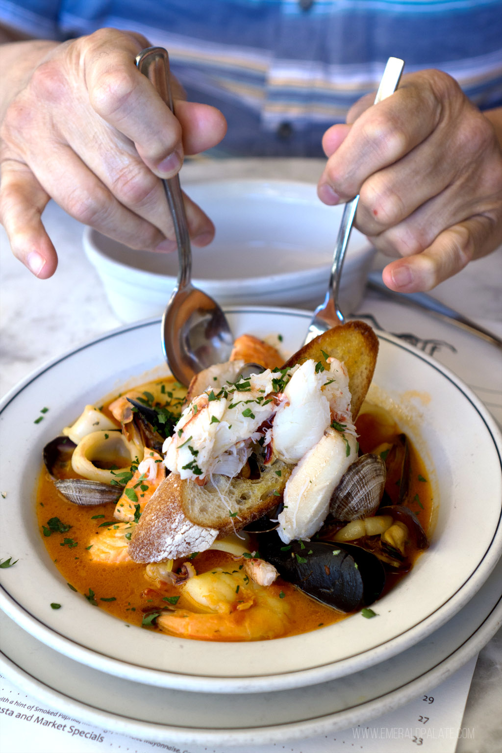 person picking up fish bouillabaisse from a rooftop restaurant with Seattle views