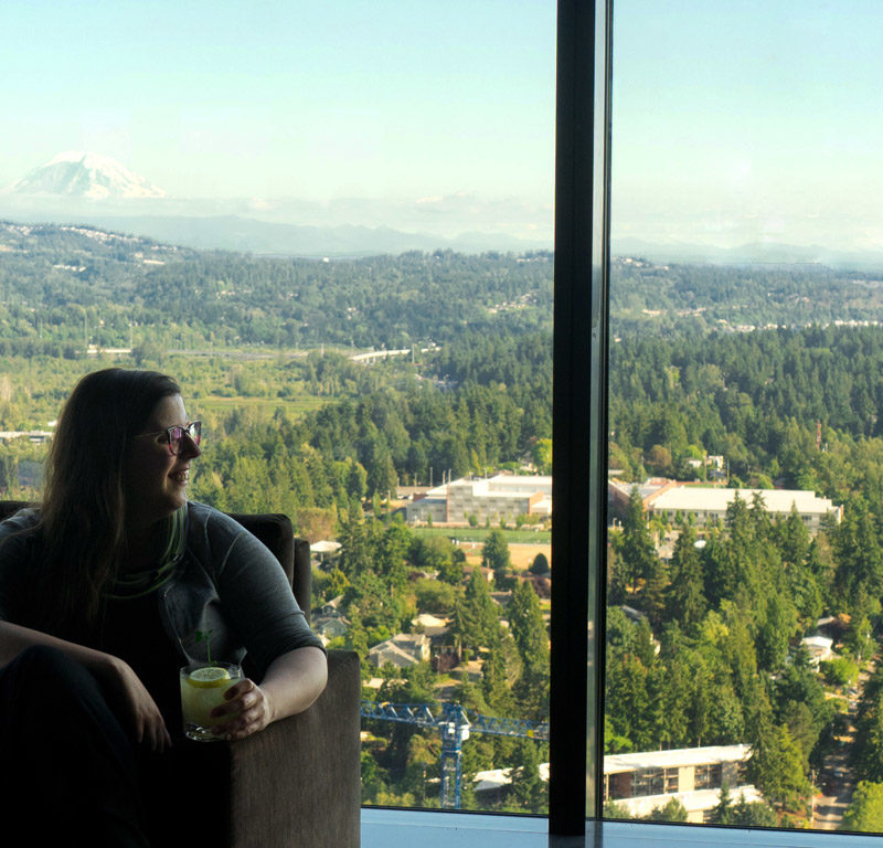 woman looking out glass window from rooftop restaurant, one of the best restaurants in Seattle with a view